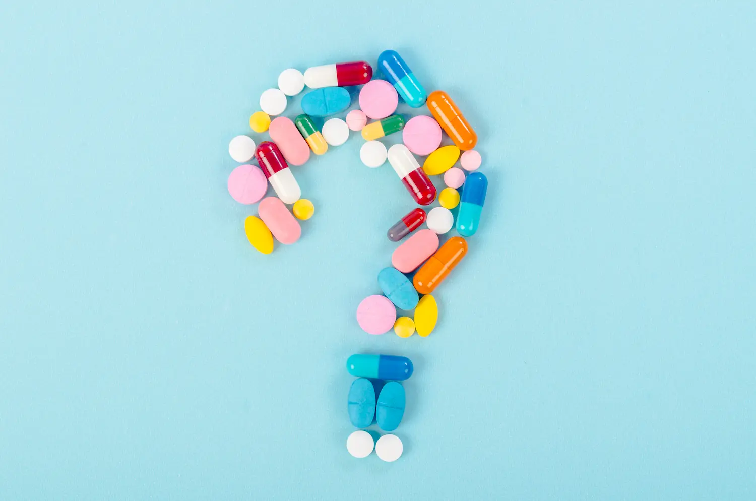 Tabletten und Kapseln als Fragezeichen geformt.