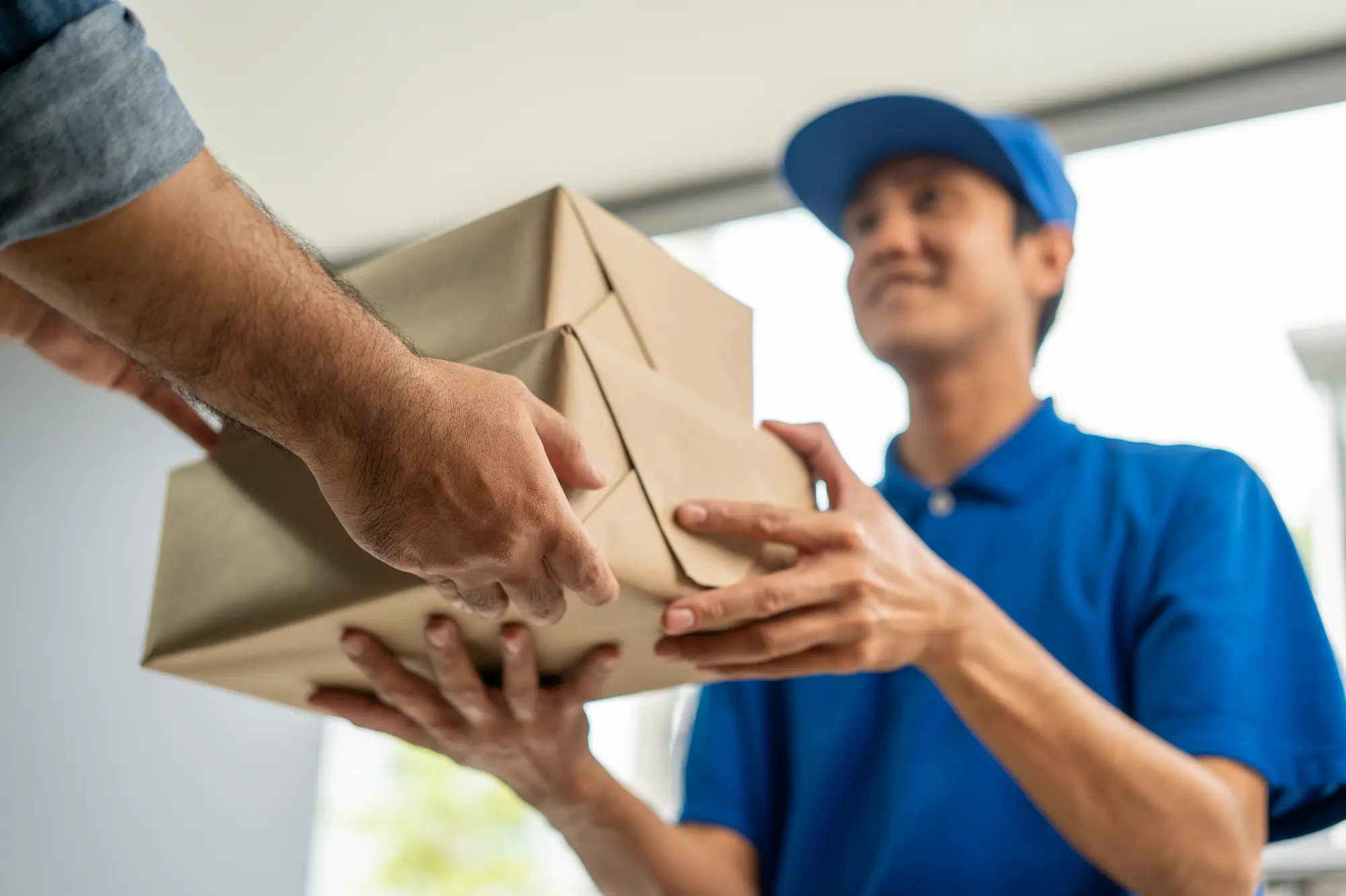 Ein Paketbote übergibt ein Paket.